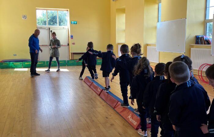 A group of school children balancing on a balance beam.