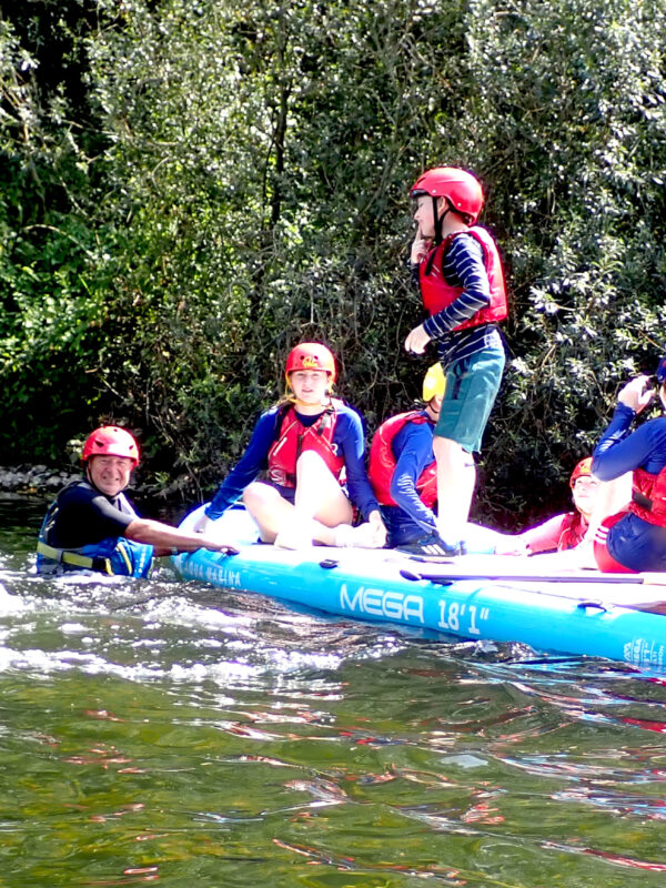 Children and volunteers on huge stand up paddle board.